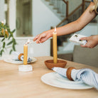 Person lighting a candle on a table with decorative items