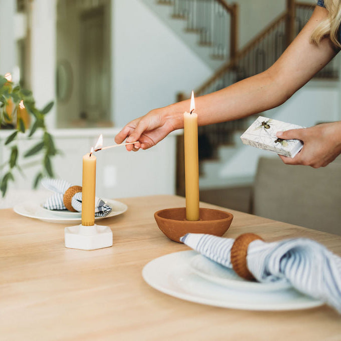 Person lighting a candle on a table with decorative items