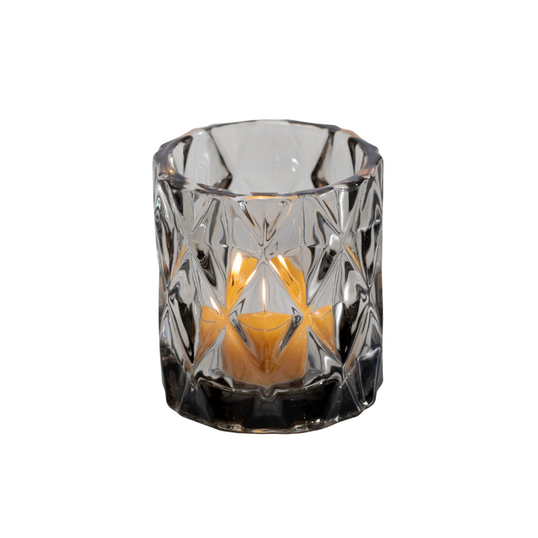 Clear glass candle holder with a candle inside on a white background